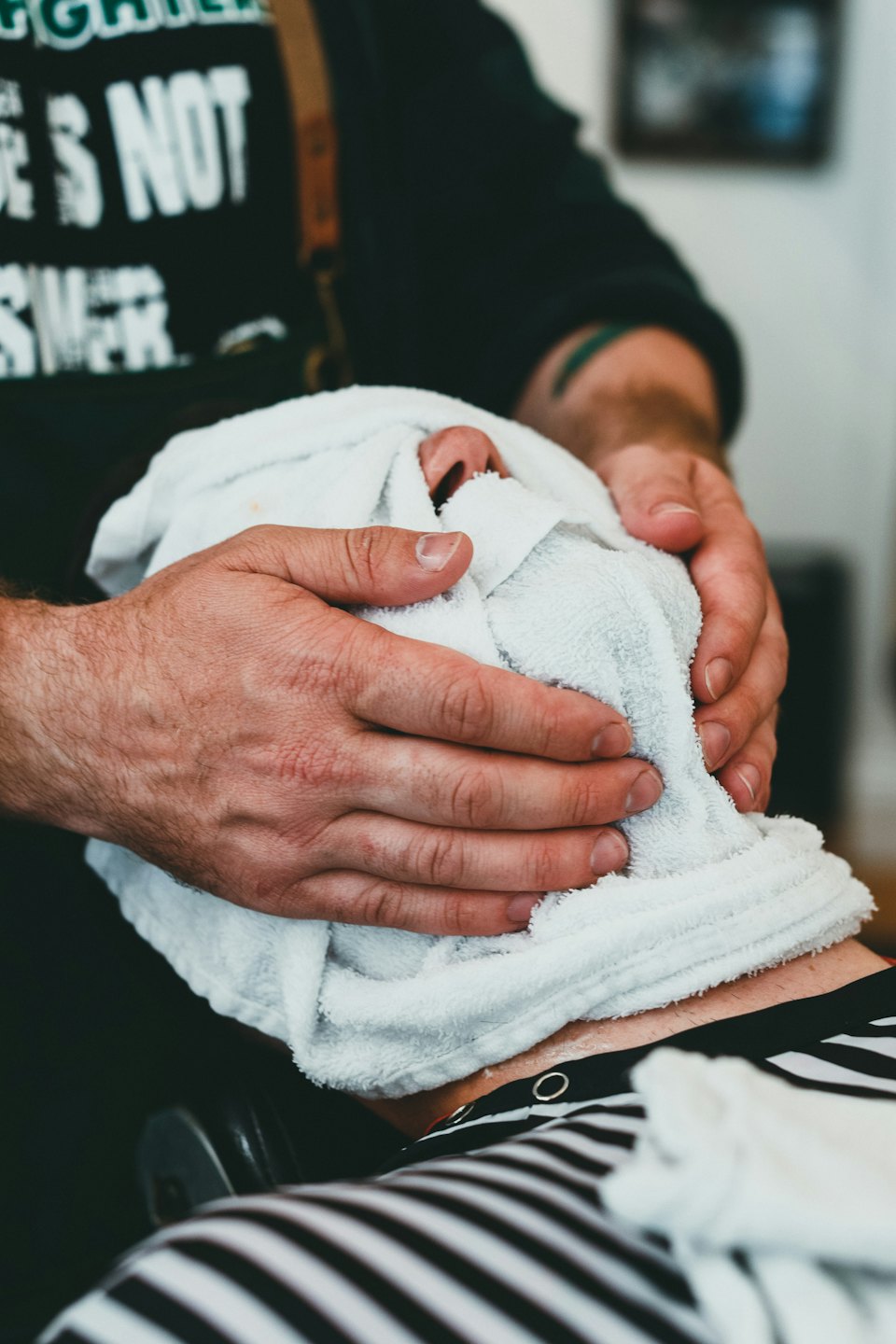 Barber's hands holding a warm towel during a hot towel shave.