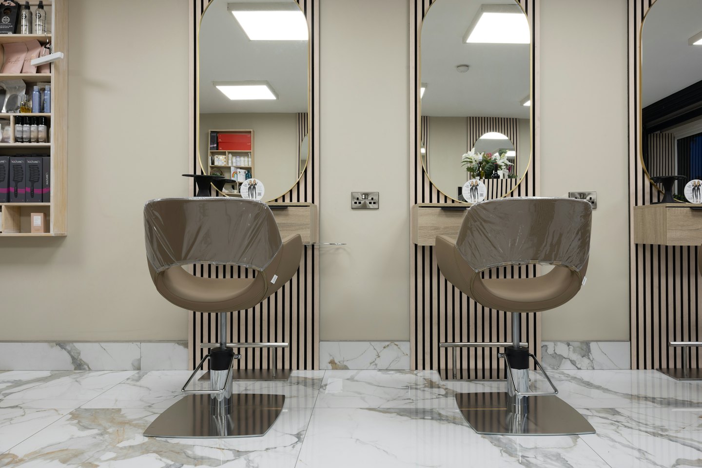 Modern hair salon with tan barber chairs and oval mirrors.