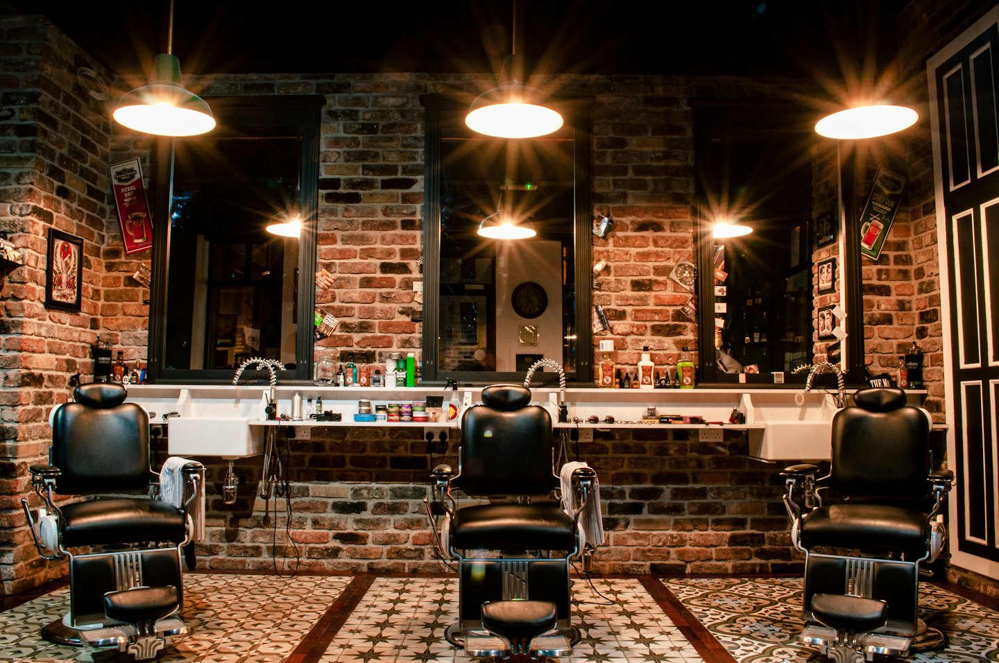 Three vintage barber chairs in a brick-walled shop.