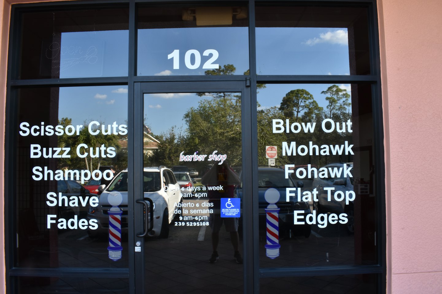 Barber shop storefront with service menu listed on glass.